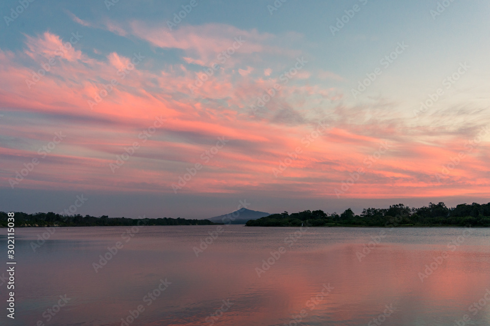Beautiful sunset sky with colorful pink clouds over river