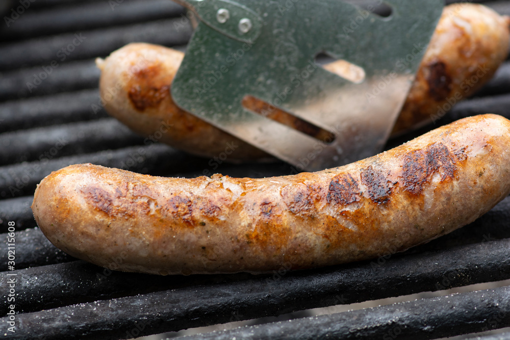 Savory brats cooking on an outdoor iron grill.