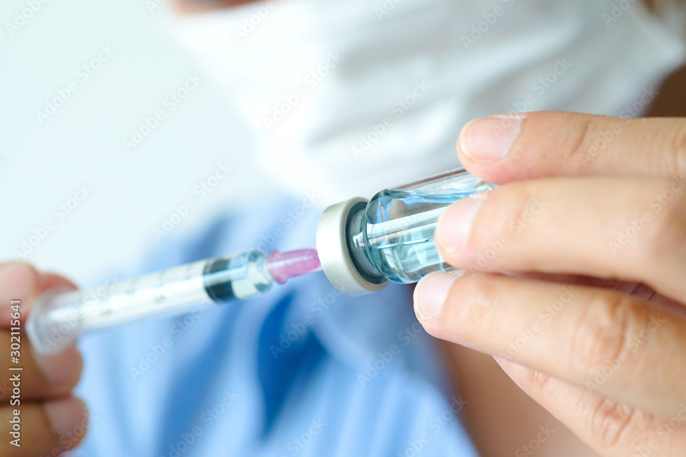 doctor's hand holds a syringe and a blue vaccine bottle at the hospital. Health and medical concepts doctor's hand holds a syringe and a blue vaccine bottle at the hospital. Health and medical concepts