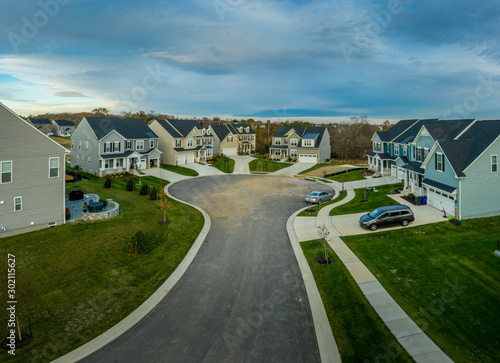 Aerial view of new construction street with luxury houses in cul-de-sac upper middle class neighborhood American real estate development in the USA with blue sky	
