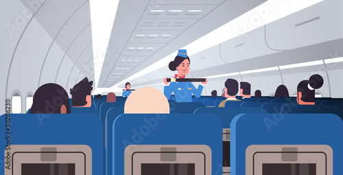 stewardess explaining passengers how to use seat belt fastening in emergency situation flight attendants in uniform safety demonstration concept airplane board interior horizontal vector illustration