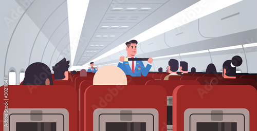 steward explaining for passengers how to use seat belt fastening in emergency situation male flight attendants in uniform safety demonstration concept modern airplane board interior horizontal vector