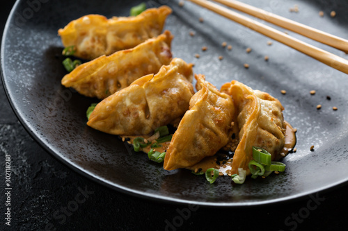 Foto Fried potstickers or dumplings on a black plate