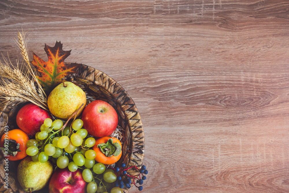 Top view of various colorful autumn fruits in a wicker basket over wooden table. Copy space. Top view of various colorful autumn fruits in a wicker basket over wooden table. Copy space.