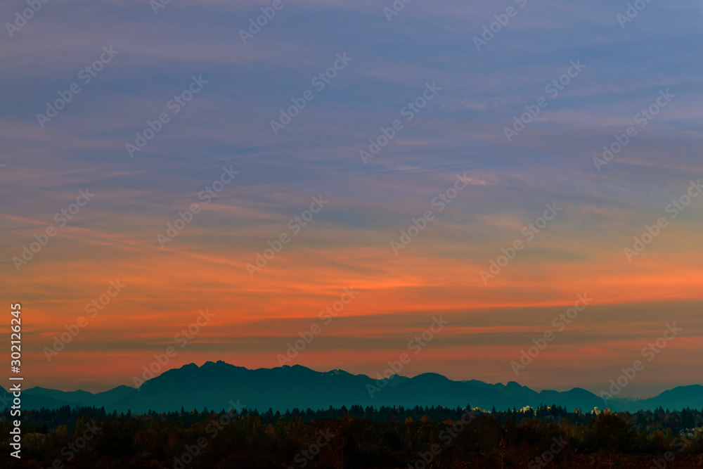 red-blue sky above the silhouettes of mountains and a red forest