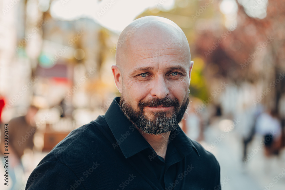 Outdoor portrait of a 50 year old happy man wearing a black shirt and glasses - obrazy, fototapety, plakaty 