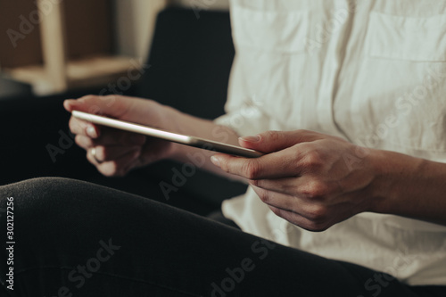 Mockup image of a woman sitting and holding white tablet pc with blank desktop screen © Nana_studio