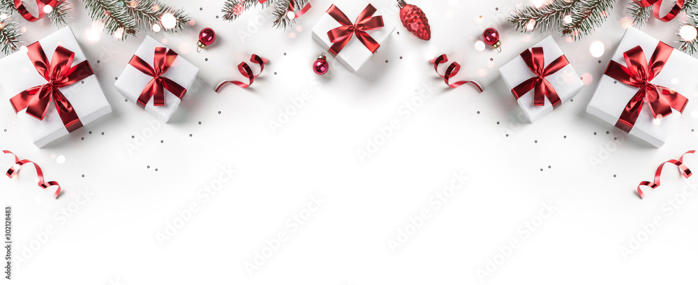 Merry Christmas card made of fir branches, gift boxes, red decoration, sparkles and confetti on white background. Xmas and New Year holiday, bokeh, light. Flat lay, top view - obrazy, fototapety, plakaty 