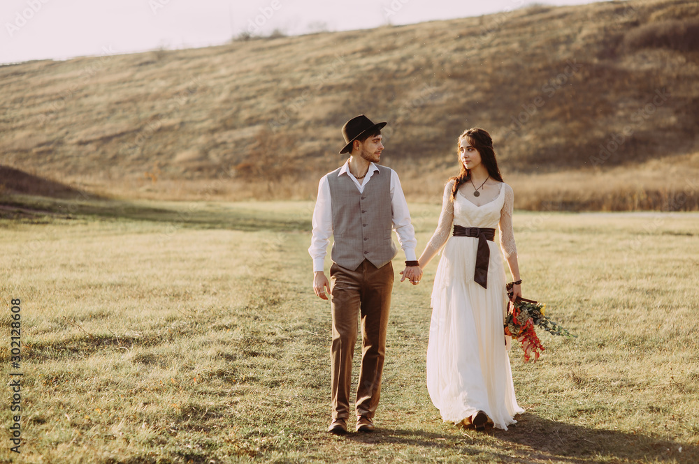 Happy husband and wife. Wedding day. Beautiful nature. Walk during the photo session. They smile at each other. Holding hands Happy husband and wife. Wedding day. Beautiful nature. Walk during the photo session. They smile at each other. Holding hands