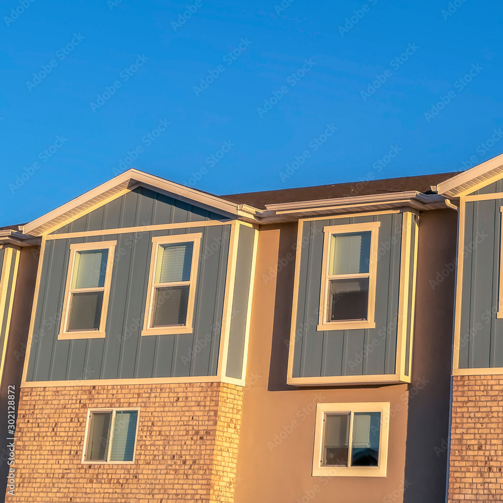 Square frame Focus on the upper storey of townhomes with blue sky background on a sunny day
