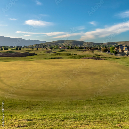 Square frame Scenic golf course landscape against houses and mountain under sky and clouds © Jason