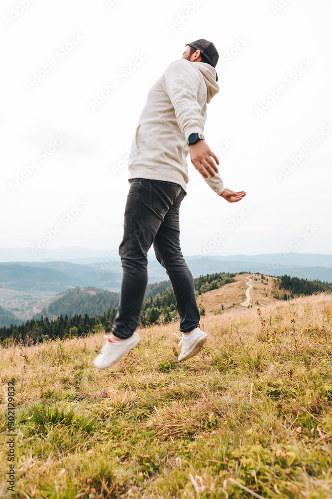 Fototapeta premium man with backpack happy jumping on the peak on the mount