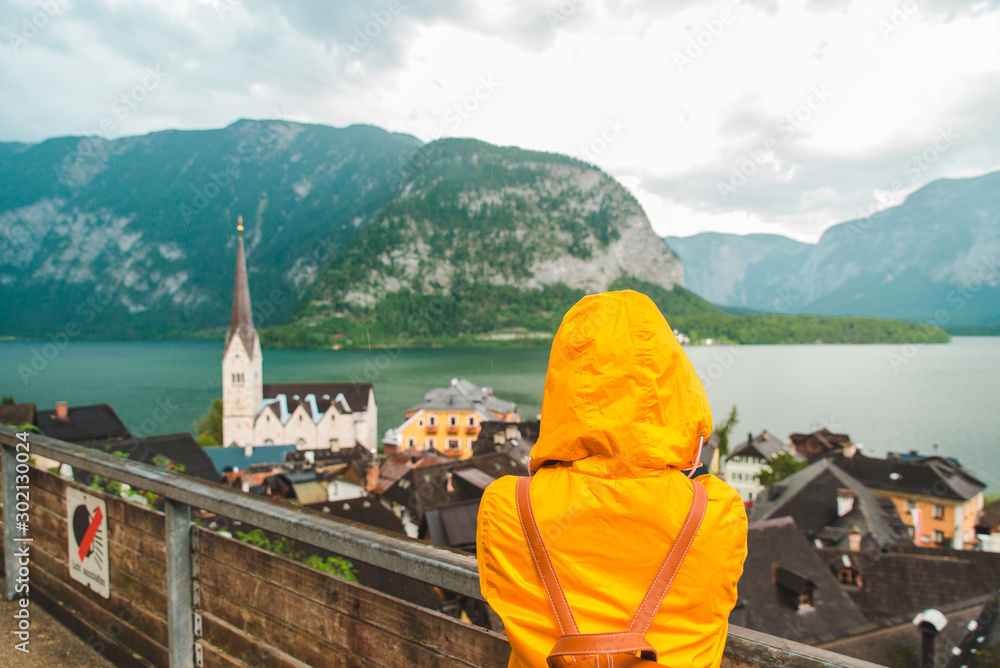 woman in yellow raincoat looking at hallstatt city