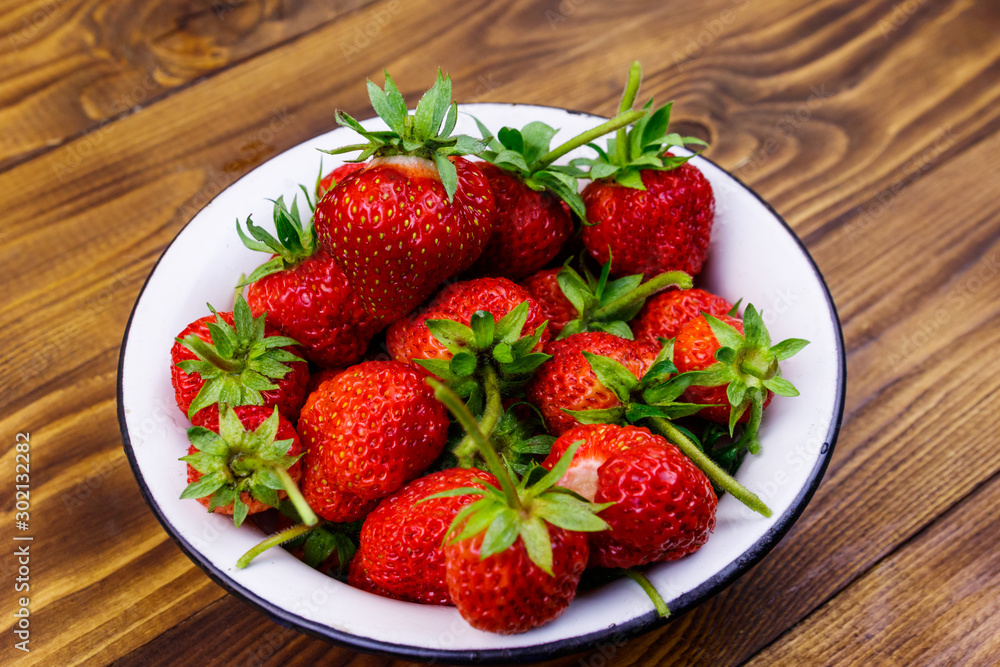 Fresh ripe strawberry in white bowl on a wooden table Fresh ripe strawberry in white bowl on a wooden table