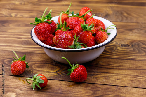 Fresh ripe strawberry in white bowl on a wooden table