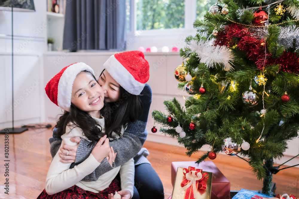 happy family, mother and daughter hug and kiss little girl and gift, toy, present box under christmas tree for christmas festival day happy family, mother and daughter hug and kiss little girl and gift, toy, present box under christmas tree for christmas festival day