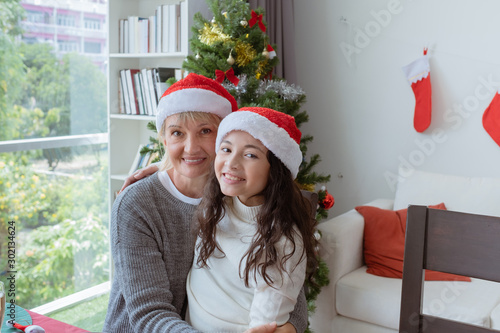 happy family, grandmother smile and hug daughter little girl and celebrate together on christmas in dining room that decorated with christmas tree christmas festival day, happy family holiday concept