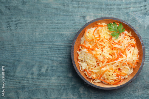 Tasty fermented cabbage with carrot on blue wooden table, top view. Space for text