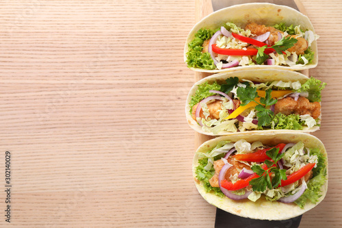 Delicious fish tacos served on wooden table, top view with space for text