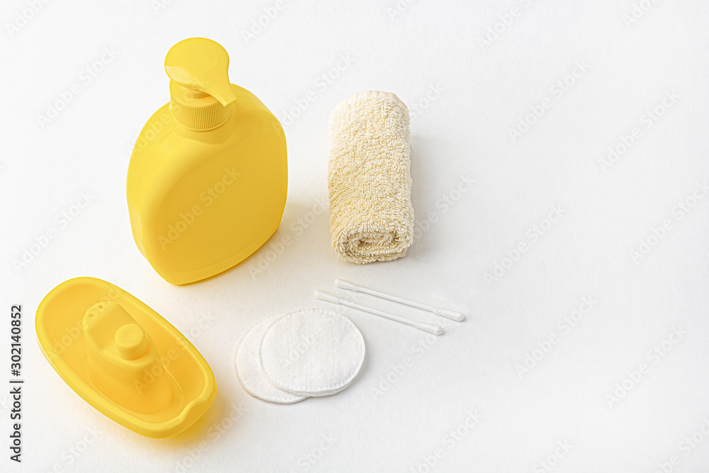 Mock up of baby bath products: yellow bottle for shampoo (shower gel, lotion), towel and cotton buds and pads isolated on white. Copy space for text, soft focus. Concept of baby bath accessories. Mock up of baby bath products: yellow bottle for shampoo (shower gel, lotion), towel and cotton buds and pads isolated on white. Copy space for text, soft focus. Concept of baby bath accessories.