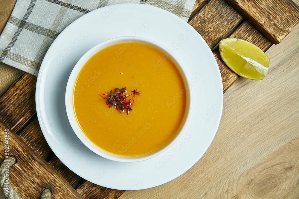 Lentil cream soup with a slice of lemon on a wooden tray in a white bowl. Healthy and vegan food. Go green. Close up Lentil cream soup with a slice of lemon on a wooden tray in a white bowl. Healthy and vegan food. Go green. Close up