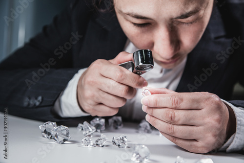 Businessman jeweler during the evaluation of jewels with magnifier. Jeweler looking at diamonds or Luxury stone through loupe evaluating gem a symbol of business success or successful finance concept