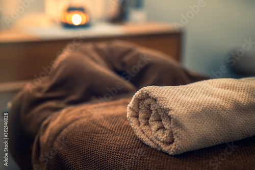 Massage table with f towel and candle in a room, spa