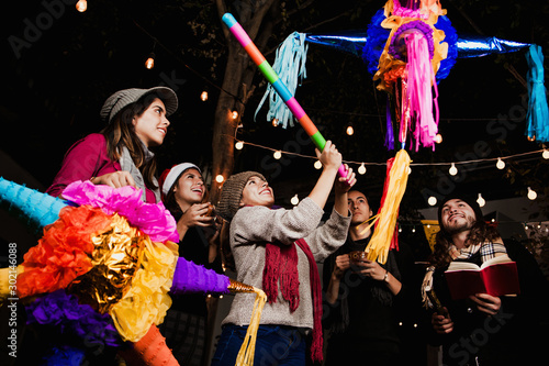 Mexican Posada friends breaking a Piñata celebrating Christmas Mexico photo