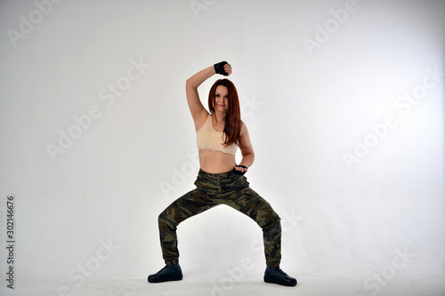 girl with red hair in a military uniform and black gloves does sports military exercises