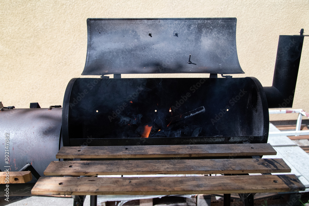 Vintage Drum Barrel Charcoal BBQ in garden.Old Barbeque with open fire. Retro Flaming Coals Offset Smoker BBQ. Concept of summer grilling, barbecue, bbq and party.
