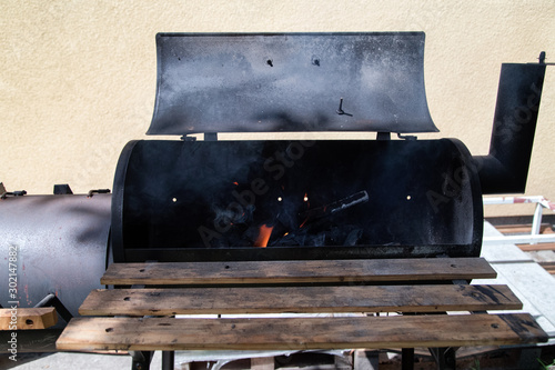 Obraz na płótnie Vintage Drum Barrel Charcoal BBQ in garden.Old Barbeque with open fire. Retro Flaming Coals Offset Smoker BBQ. Concept of summer grilling, barbecue, bbq and party. w salonie