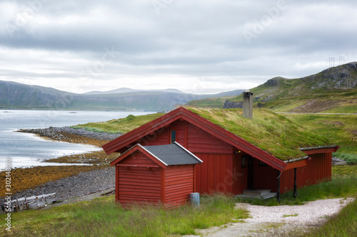 Traditional Norwegian red house on the fjord in cloudy weather
