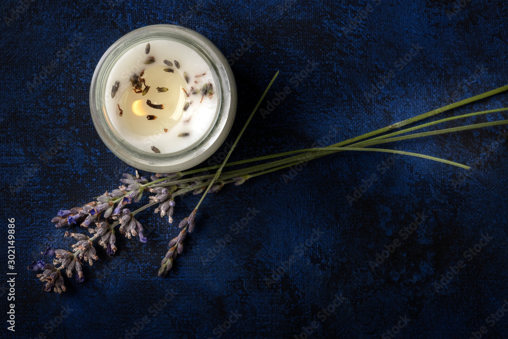 A burning lavender scented candle, overhead shot on a dark background with a place for text. Zero waste Christmas concept, a handmade New Year gift in a recycled glass jar - obrazy, fototapety, plakaty 