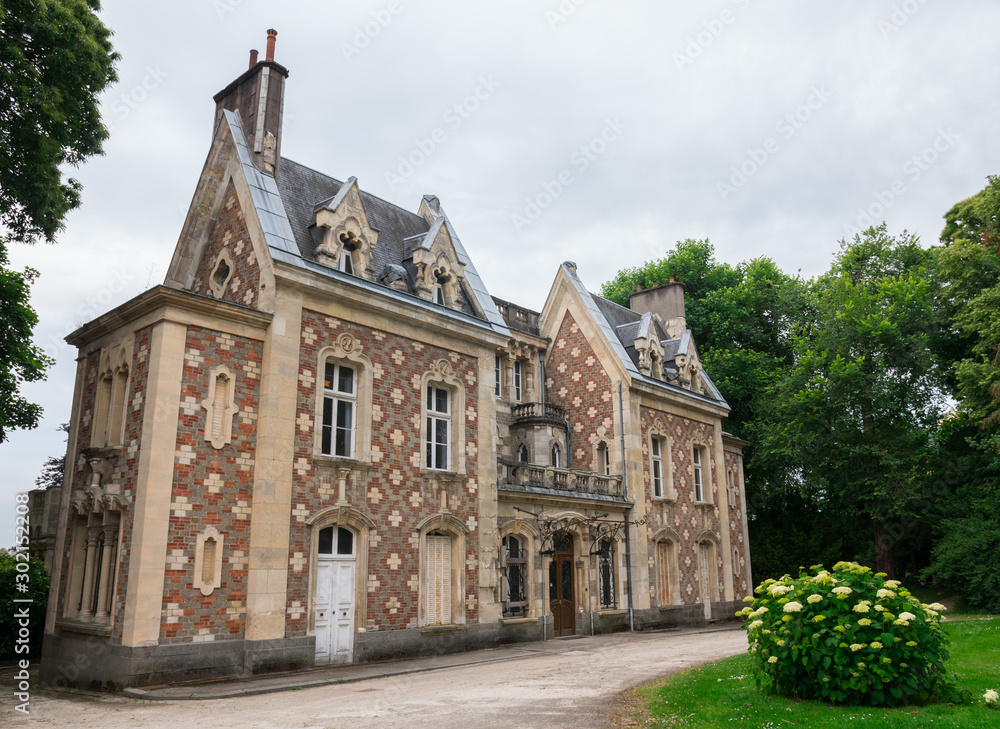 Music academy of Flers (Normandy, France). French conservatory. Beautiful ancient building, mansion with a stone & red brick architecture, surrounded by nature. Cloudy day. Wide-angle shot.