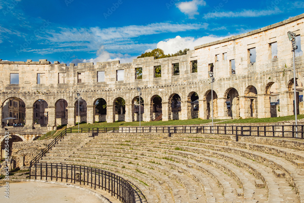 Monumental ancient Roman arena in Pula, Istria, Croatia, interior of historic amphitheater, wide angle view of high walls on blue sky background