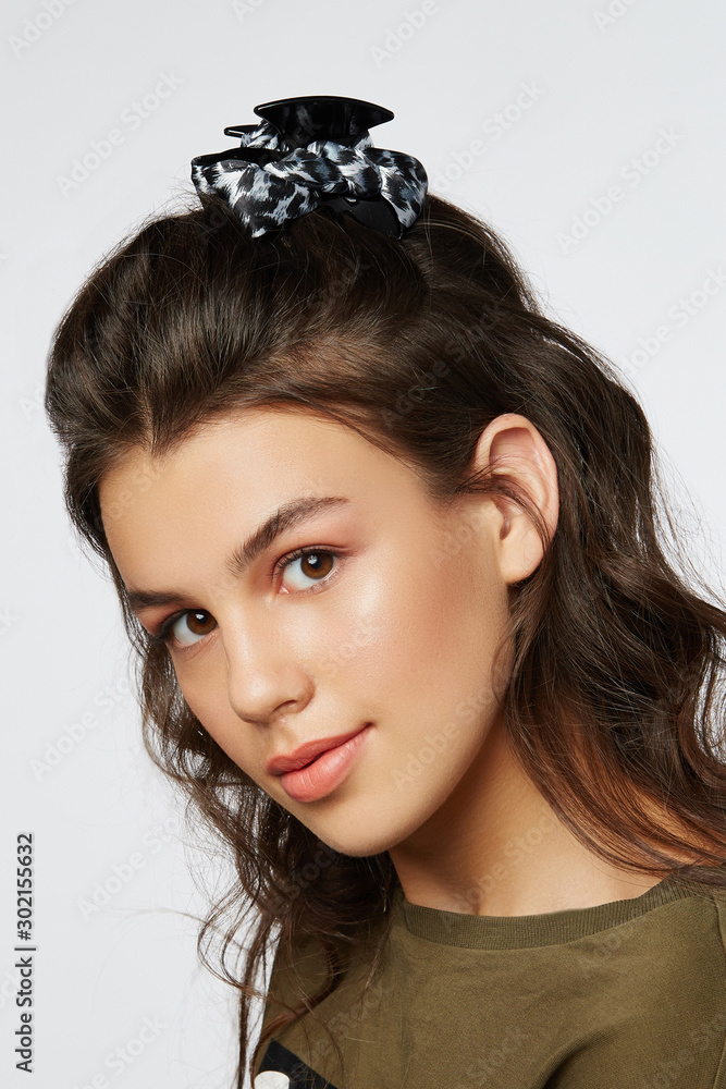 Closeup half-turn face portrait of girl with dark wavy hair, wearing khaki  t-shirt. Her hair is pulling with black hairpin crab with grey fabric bow  with leopard print. Stock Photo | Adobe