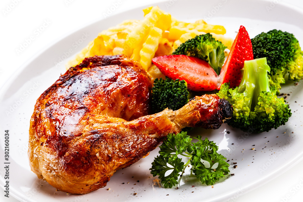 Grilled chicken leg with chips and vegetables on white background