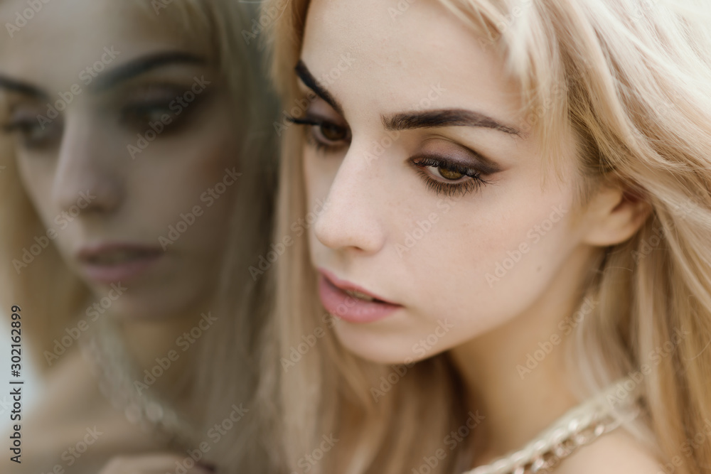 Portrait of a beautiful blonde girl. Reflection in the mirror.