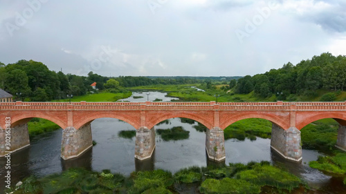 Flying Over the Widest Waterfall in Europe in Latvia Kuldiga and Brick Bridge Across the River Venta in the Evening After Sunrise. Aereal Dron Shot.