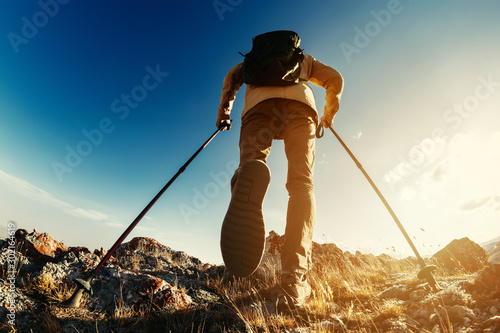 Hiker goes with trekking poles uphill