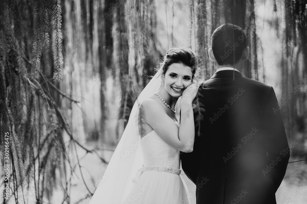 Obraz premium Newly married couple running and jumping in park while holding hands
