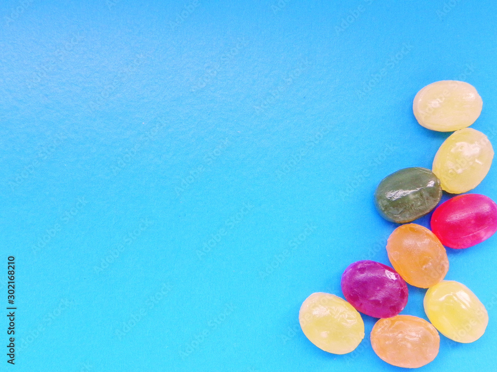 Multi-colored lollipops on a blue background, arrangement in the corner, for cards, backgrounds Multi-colored lollipops on a blue background, arrangement in the corner, for cards, backgrounds