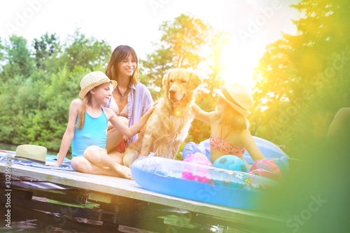 Happy family with their dog in lake with yellow lens flare in background