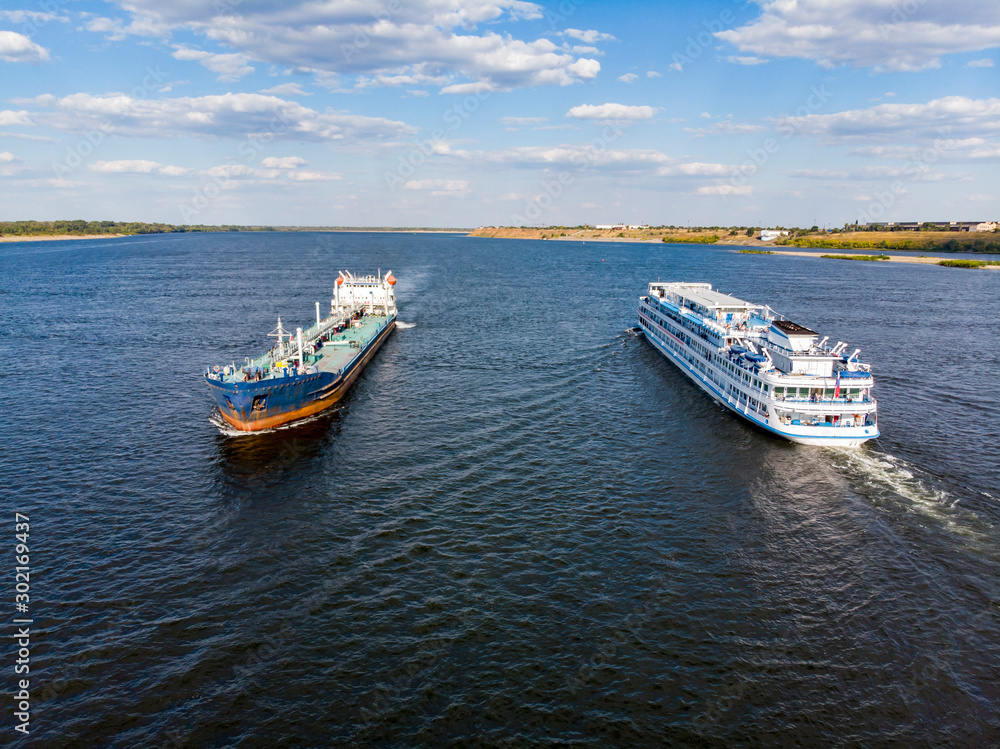 A cruise ship with tourists passes a tanker loaded with oil and goes down the Volga to Astrakhan. Volgograd. Russia