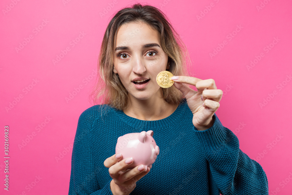 Woman holding a physical bitcoin cryptocurrency in her hand. Thinking about question, pensive expression, looks incredulous. Change in the growth and fall of cryptocurrency. Woman holding a physical bitcoin cryptocurrency in her hand. Thinking about question, pensive expression, looks incredulous. Change in the growth and fall of cryptocurrency.