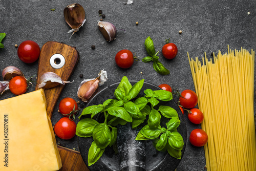 Italian food ingredients for spaghetti: parmesan, pasta, tomatoes, basil, garlic