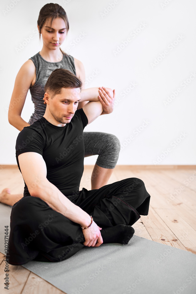 Young man and woman doing stretching training at gym