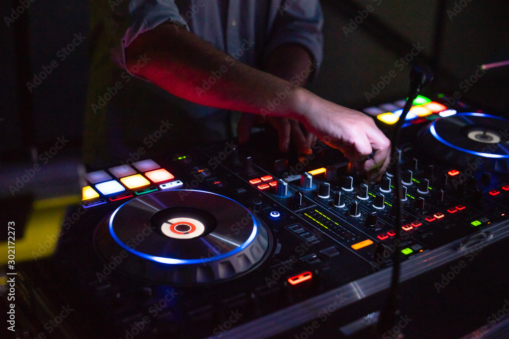 Obraz premium DJ desk in a nightclub party with hands. Studio DJ equipment glowing with light