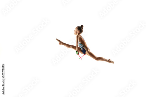 Little flexible girl isolated on white studio background. Little female model as a rhythmic gymnastics artist in bright leotard. Grace in motion, action and sport. Doing exercises with the maces.