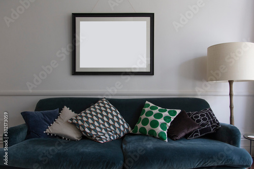 Empty picture frame hanging above a blue sofa in a living room photo